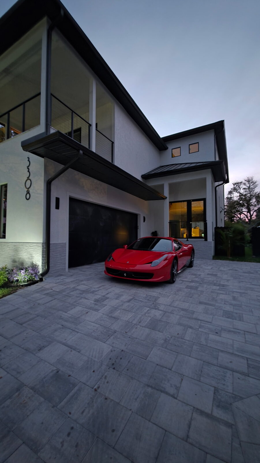 Red Ferrari 458 with tinted windows parked at a Naples, FL luxury home after tint installation by Tamiami Tint of Naples