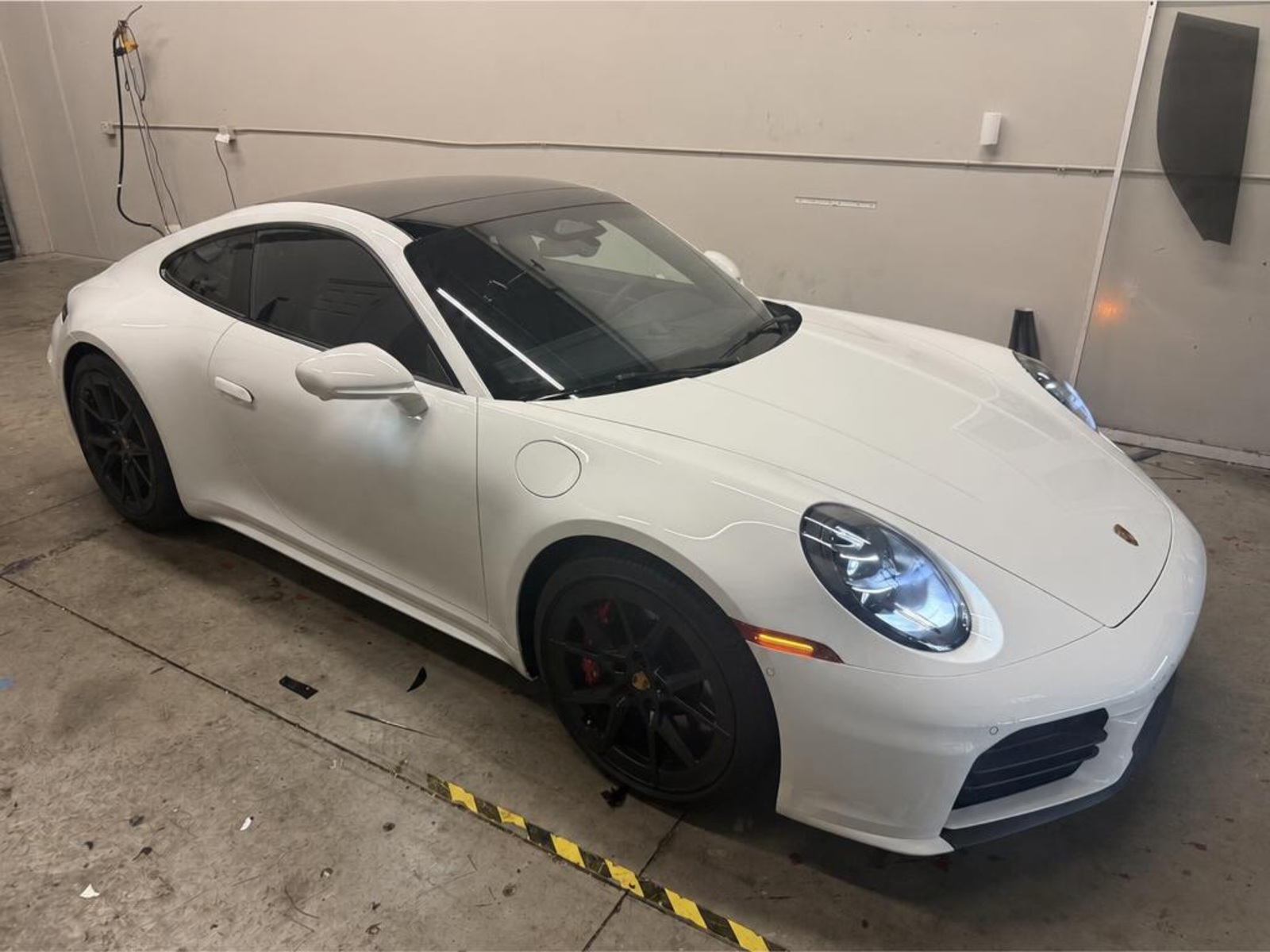 White Porsche 911 with freshly tinted windows parked inside the Tamiami Tint of Naples shop