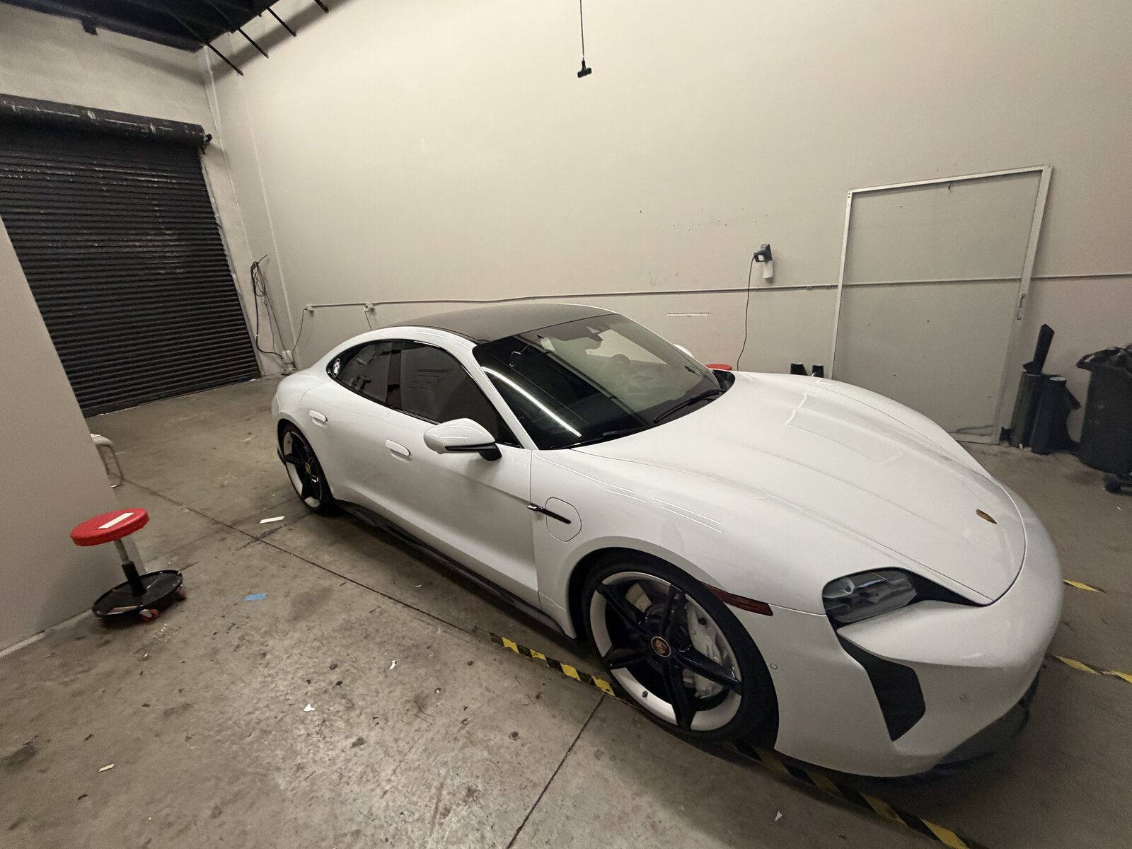 White Porsche Taycan electric vehicle with freshly tinted windows at Tamiami Tint of Naples